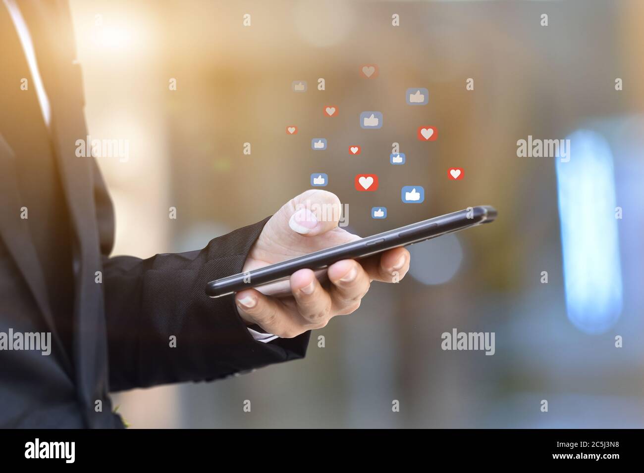 Primo piano delle mani di un uomo d'affari utilizzando lo smartphone mobile con l'icona dei social media. Idea per il business, il marketing online e la tecnologia. Foto Stock