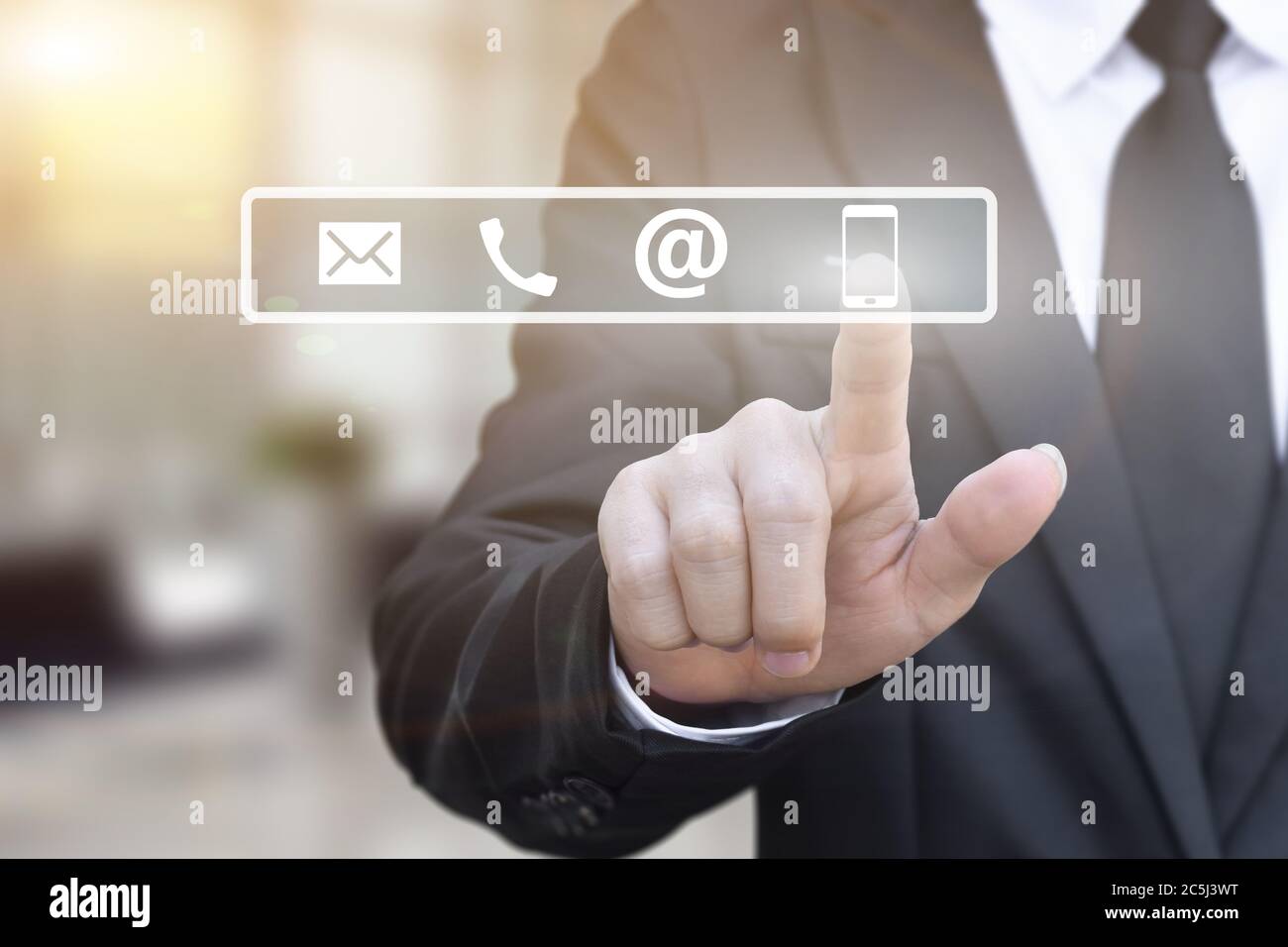 Mano di uomo d'affari premendo un contatto icone su offuscare ufficio luci sfondo. Foto Stock