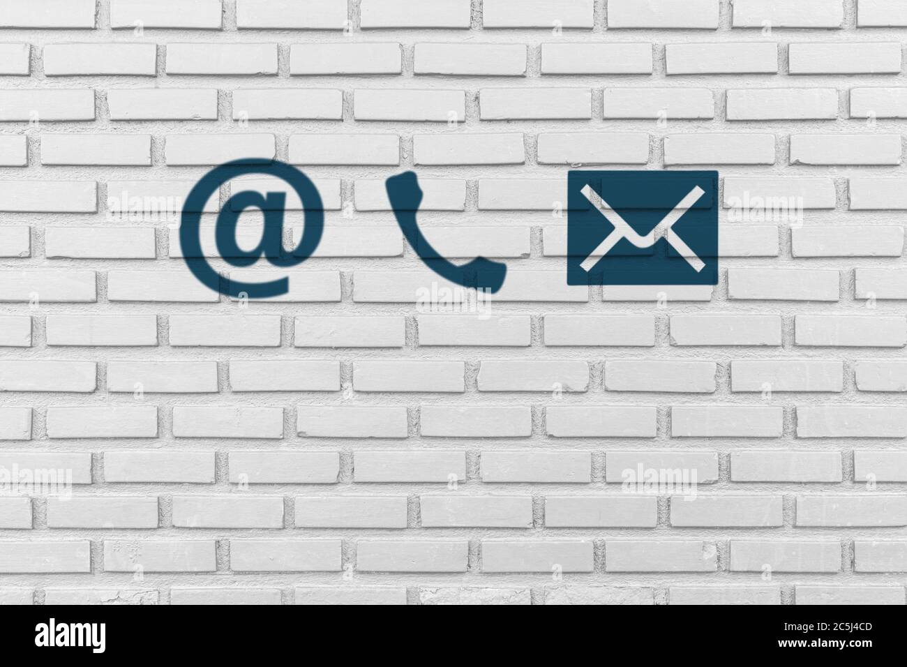 Contattaci. Icone di telefono, e-mail e posta dipingono su una parete bianca in mattoni Foto Stock