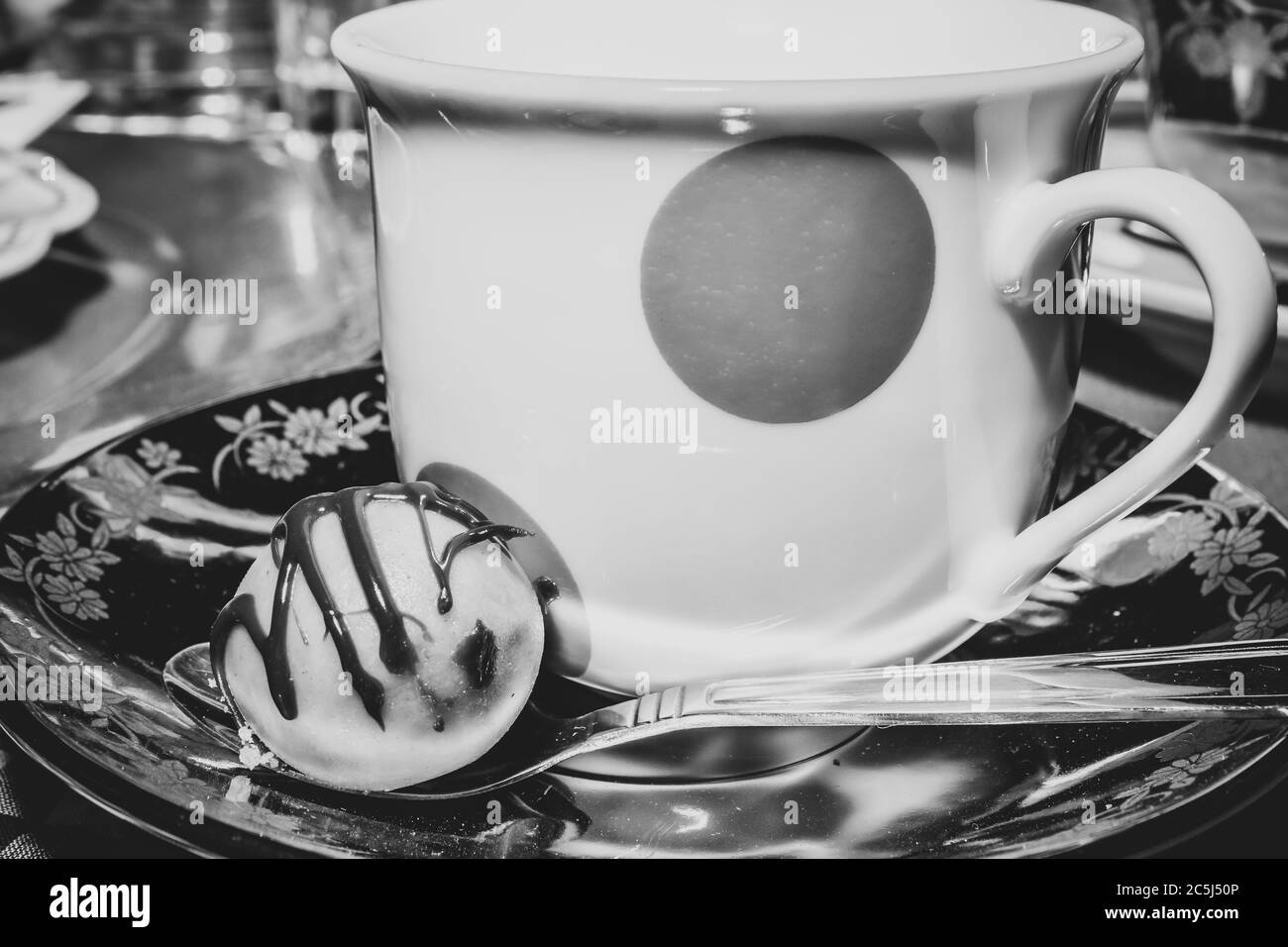 Festa del tè colorato con una tazza di tè in un teacup punteggiato di giallo e dolce cioccolata su un piatto e un cucchiaino d'argento Foto Stock