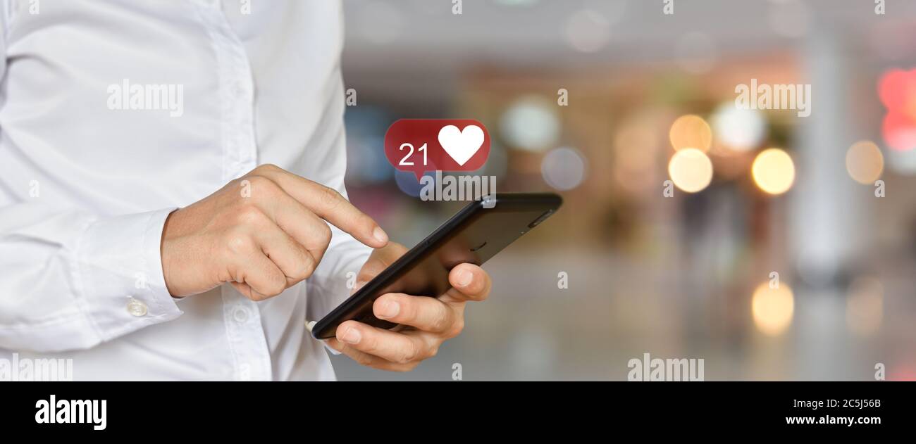 Primo piano di un uomo che utilizza lo smartphone mobile con icone social e multimediali. Concetto di tecnologia di marketing o aziendale. Foto Stock