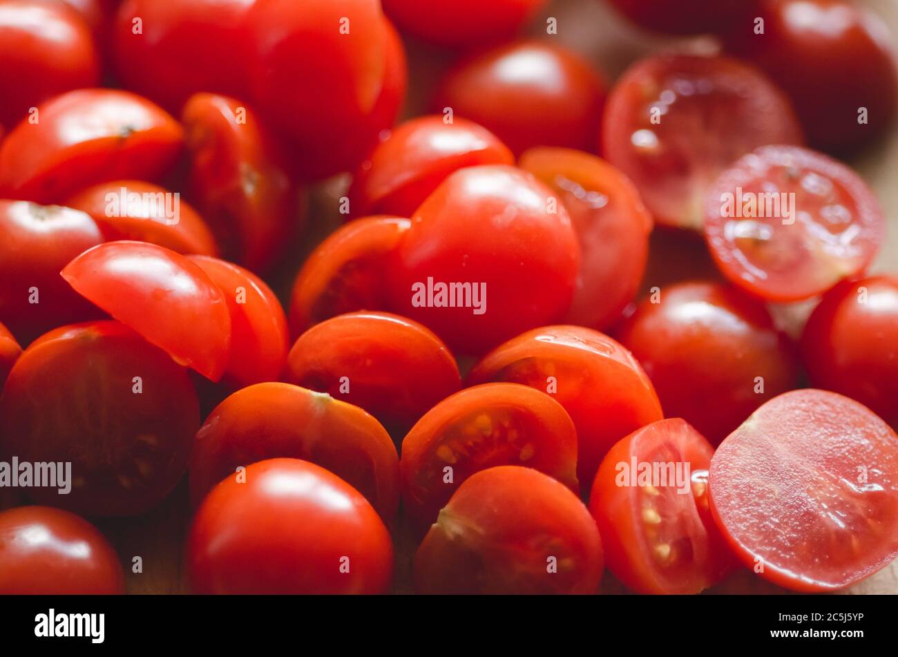 Primo piano di pomodori ciliegini rossi su scrivania in legno in cucina, interni, luce naturale Foto Stock