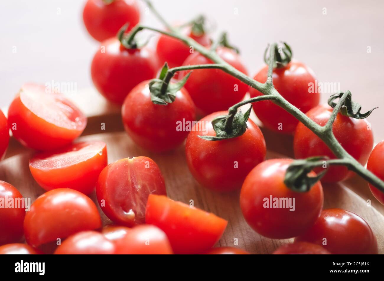 Primo piano di pomodori ciliegini rossi su scrivania in legno in cucina, interni, luce naturale Foto Stock