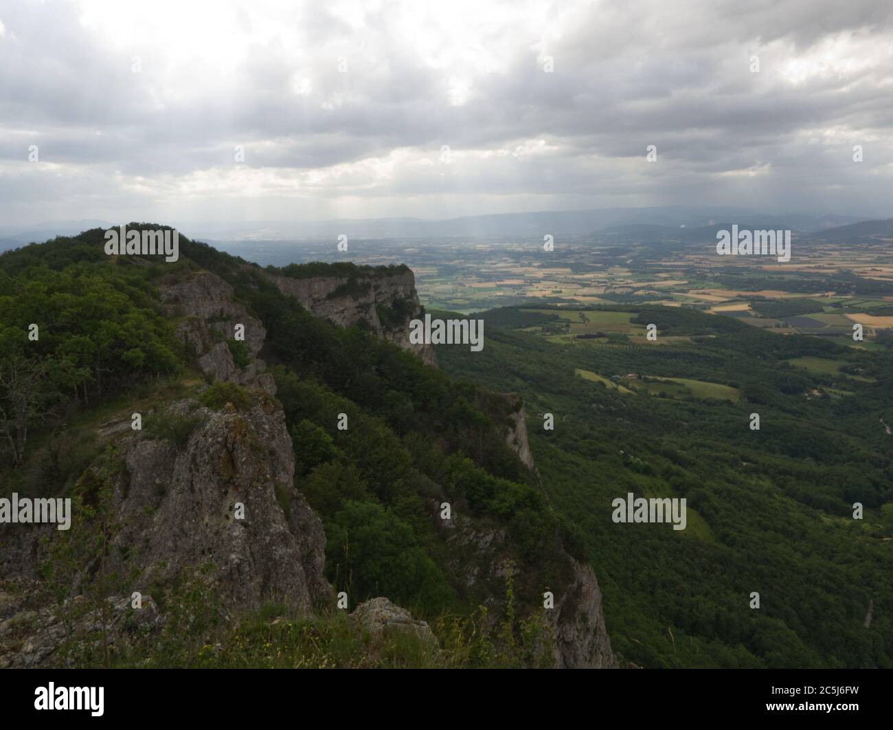 Vista prospettica su una scogliera con pianura sullo sfondo con luce e ombre effetti di nuvole in Drome Francia Foto Stock
