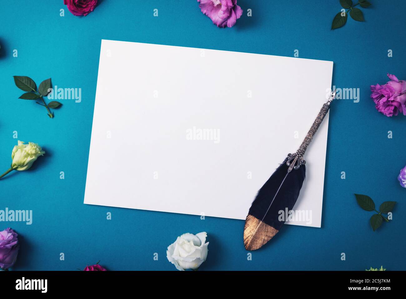 carta bianca con penna di quill vintage e fiori su sfondo blu Foto Stock