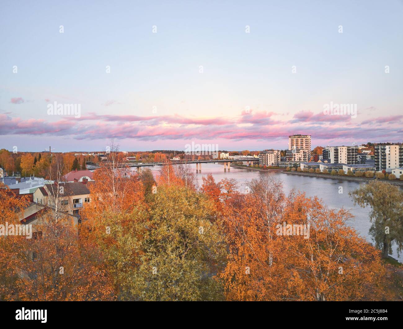 Vista aerea della piccola città finlandese d'autunno e del fiume al tramonto. Joensuu, Finlandia Foto Stock