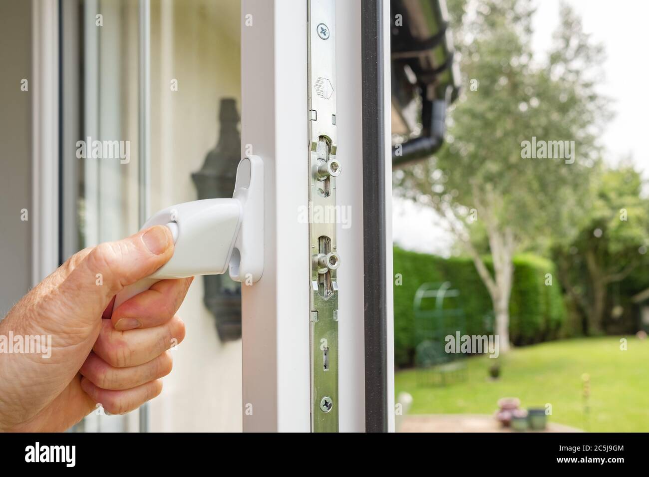 Persona che ha visto l'apertura in una finestra di nuovo installato doppio vetro su una casa annesso. Sul telaio del finestrino sono visibili più serrature. Foto Stock