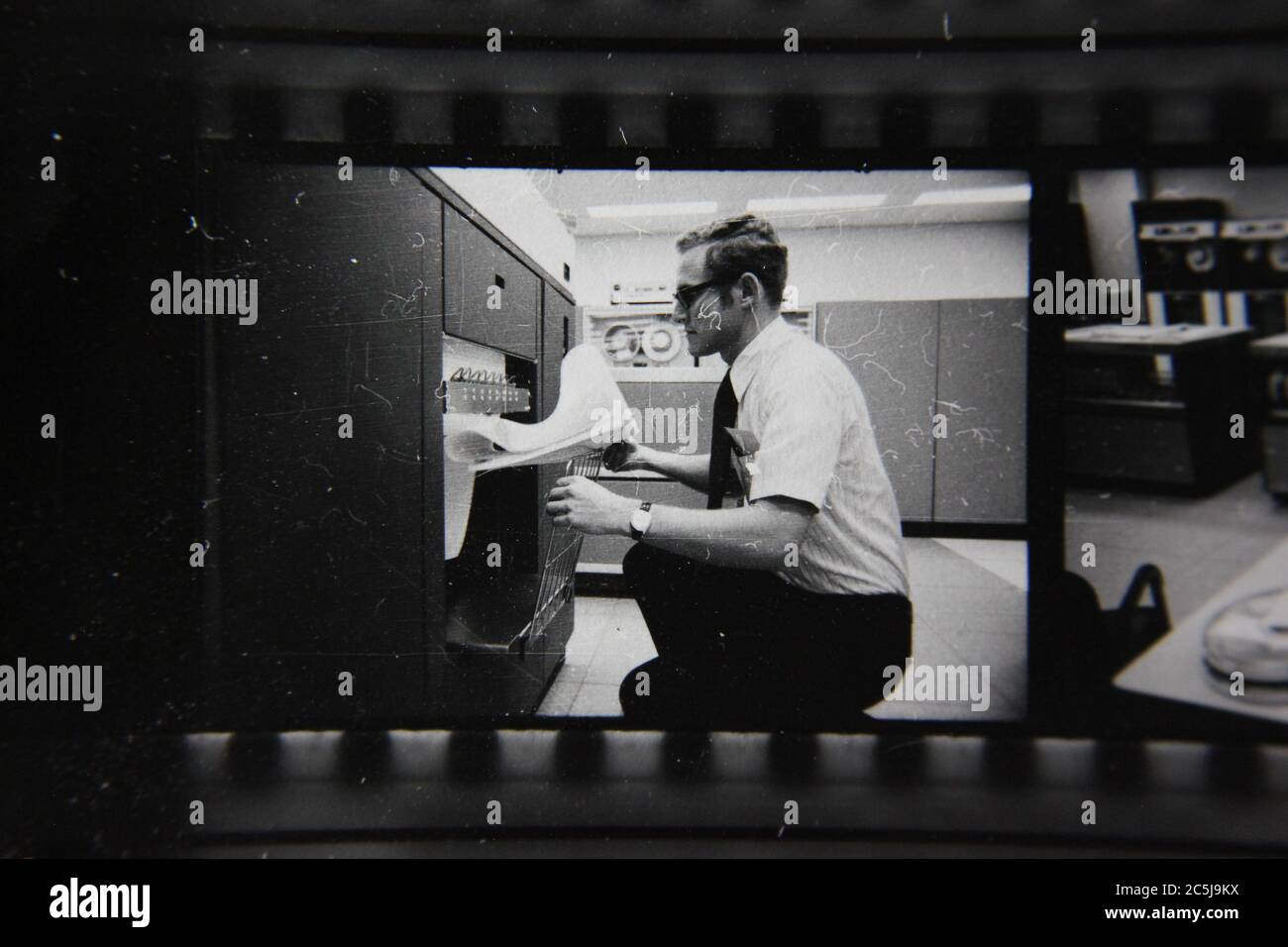 Fine anni '70 vintage contatto stampa in bianco e nero fotografia di un uomo che sovrintende un computer in una sala computer. Foto Stock