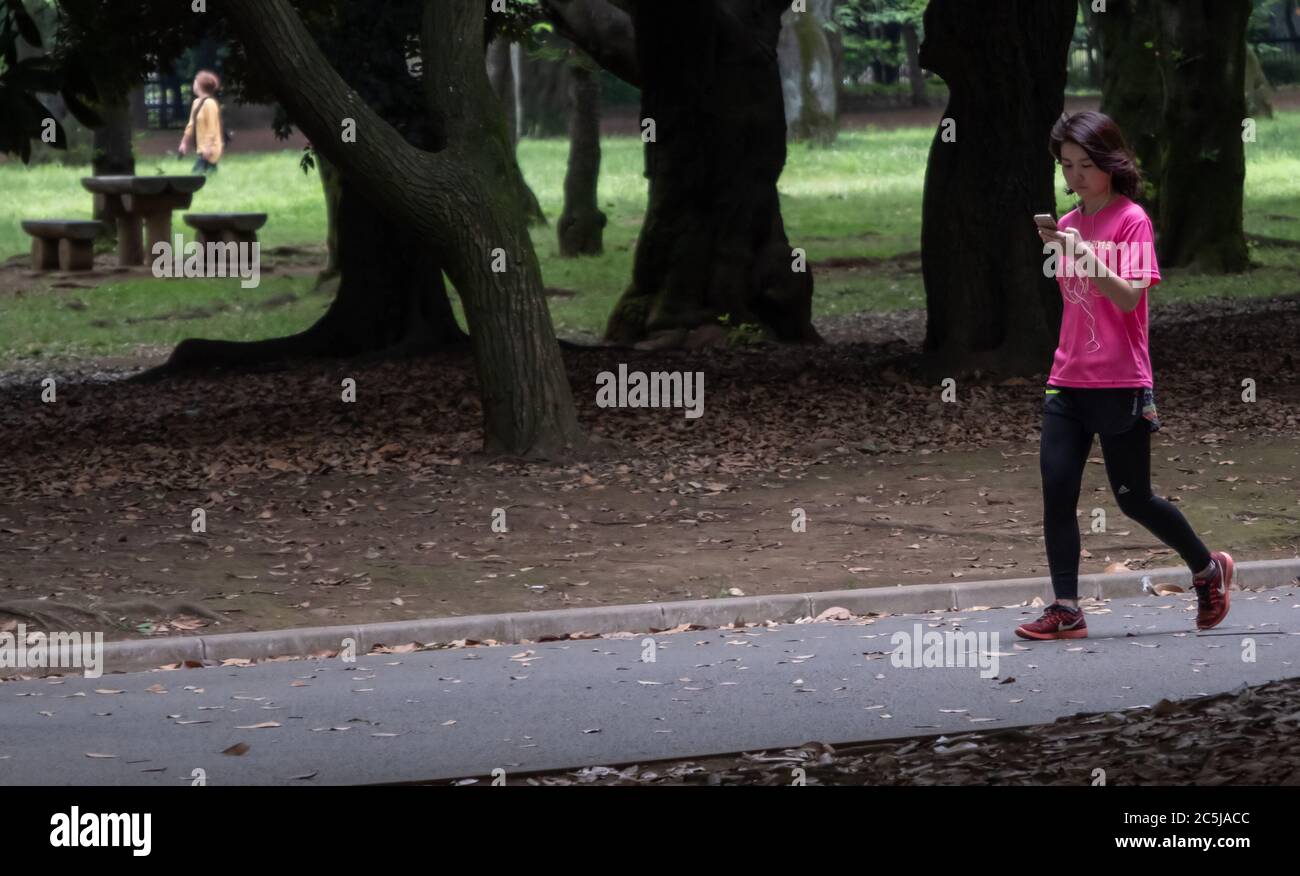 Donna con smartphone a Yoyogi Park, Tokyo, Giappone Foto Stock