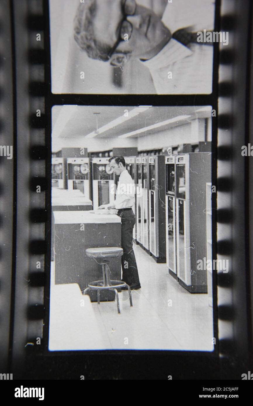 Fine anni '70 vintage contatto stampa in bianco e nero fotografia di un uomo che sovrintende un computer in una sala computer. Foto Stock