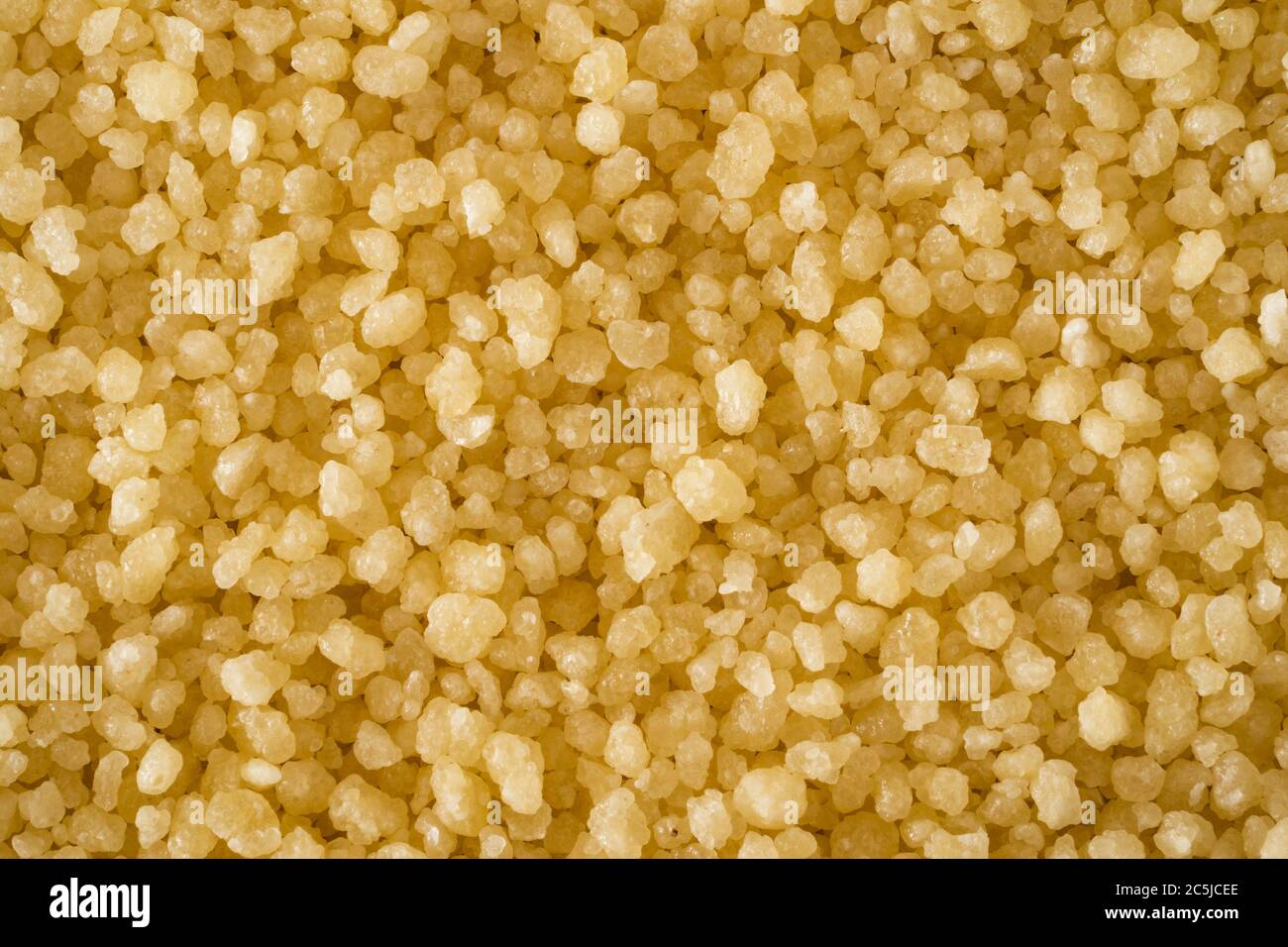 Un macro closeup di couscous crudo - minuscoli granuli di pasta fatti di grano duro / semola al vapore e essiccati utilizzati per cucinare un piatto nordafricano Foto Stock