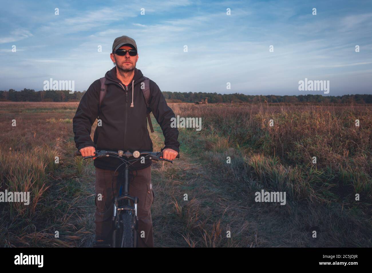 Un uomo in bicicletta su una strada sterrata, una sera giorno d'autunno Foto Stock