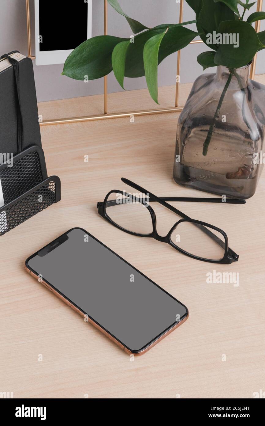 Telefono cellulare minimale per l'ufficio, con scrivania in legno e grigio mockup parete Foto Stock