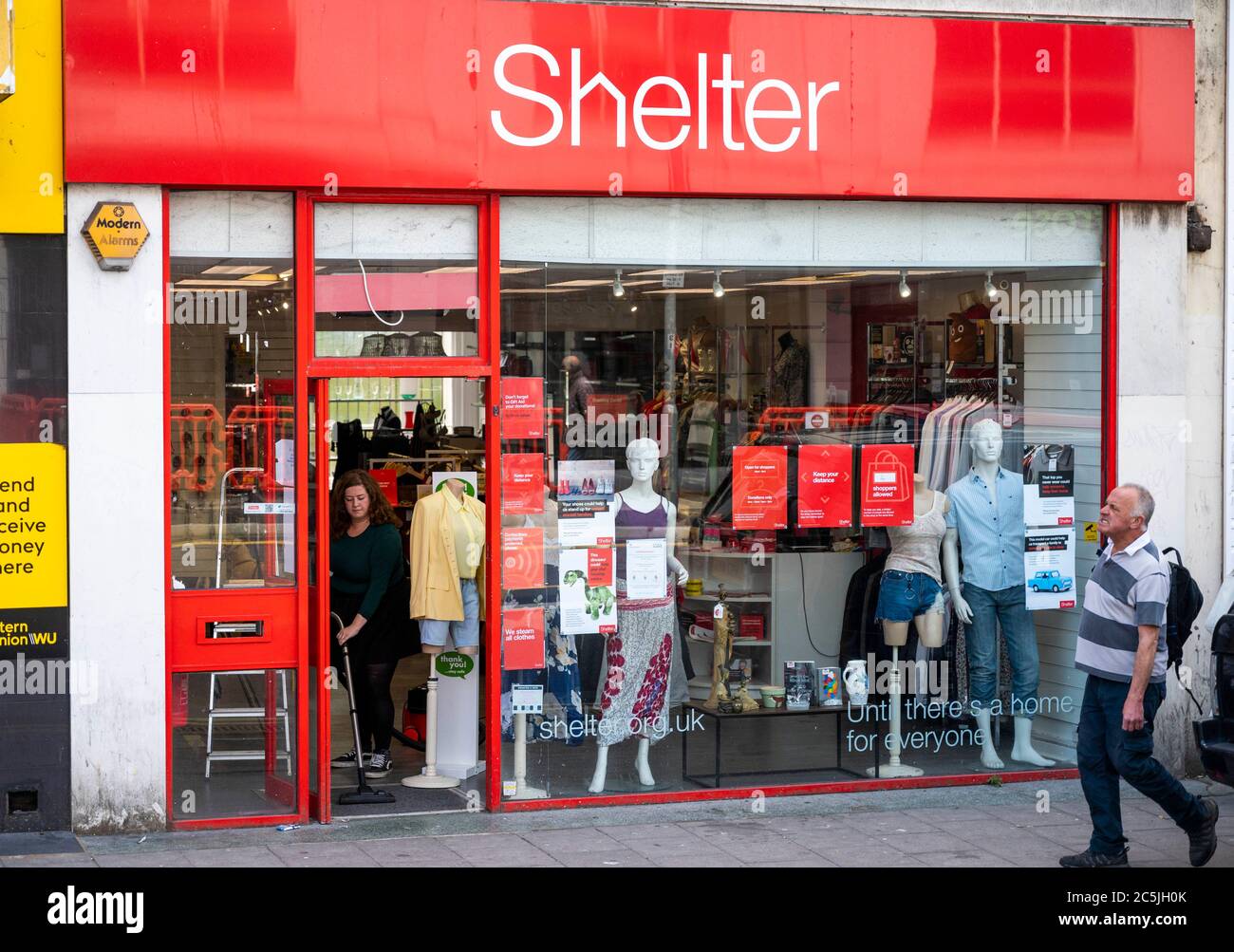 Membro del personale che si è fatto un'opera di beneficenza presso il negozio Shelter di Western Road Brighton UK Foto Stock