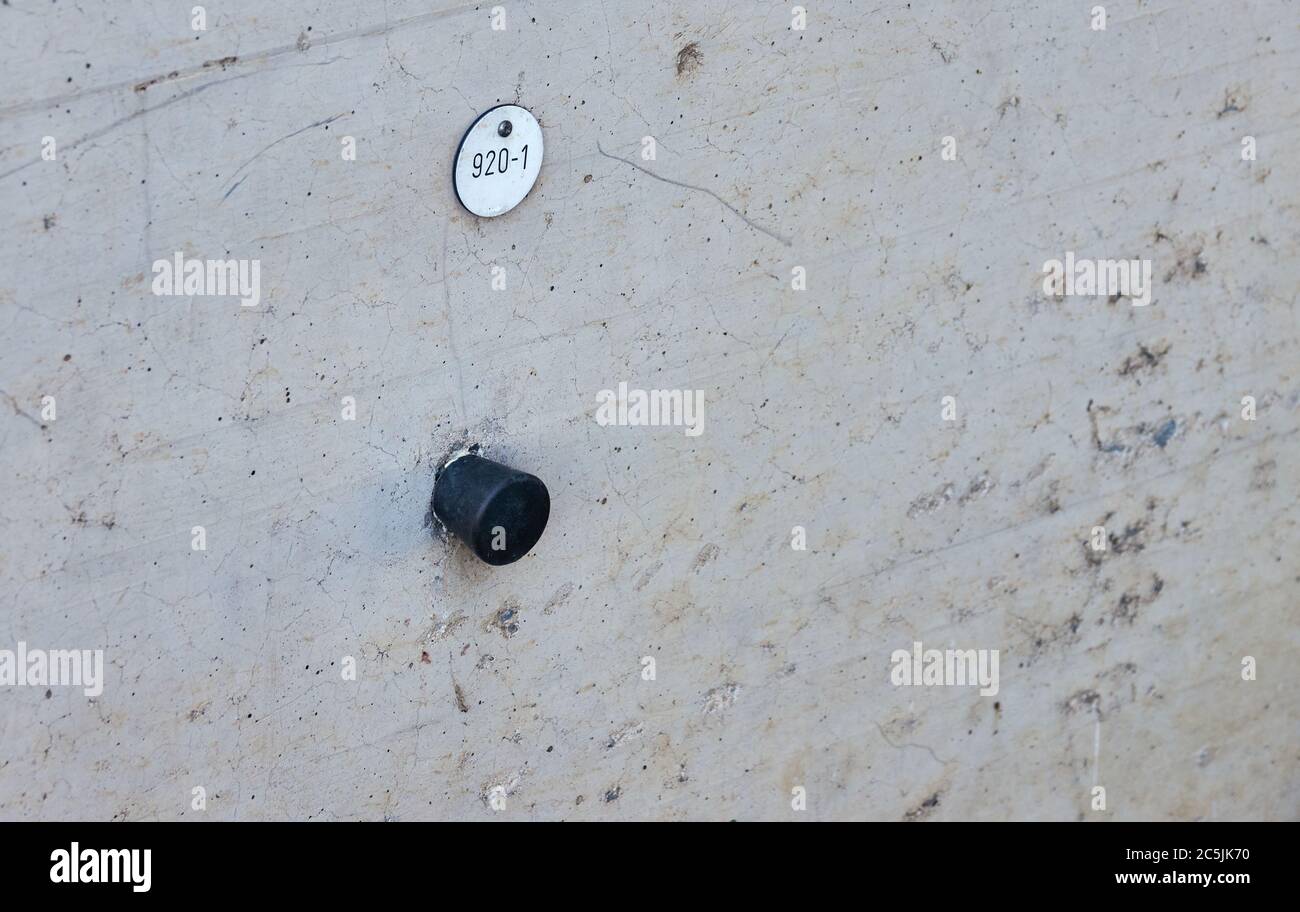 Bullone in metallo nero con il numero 920-1 nel calcestruzzo di un ponte per misurare le altezze Foto Stock