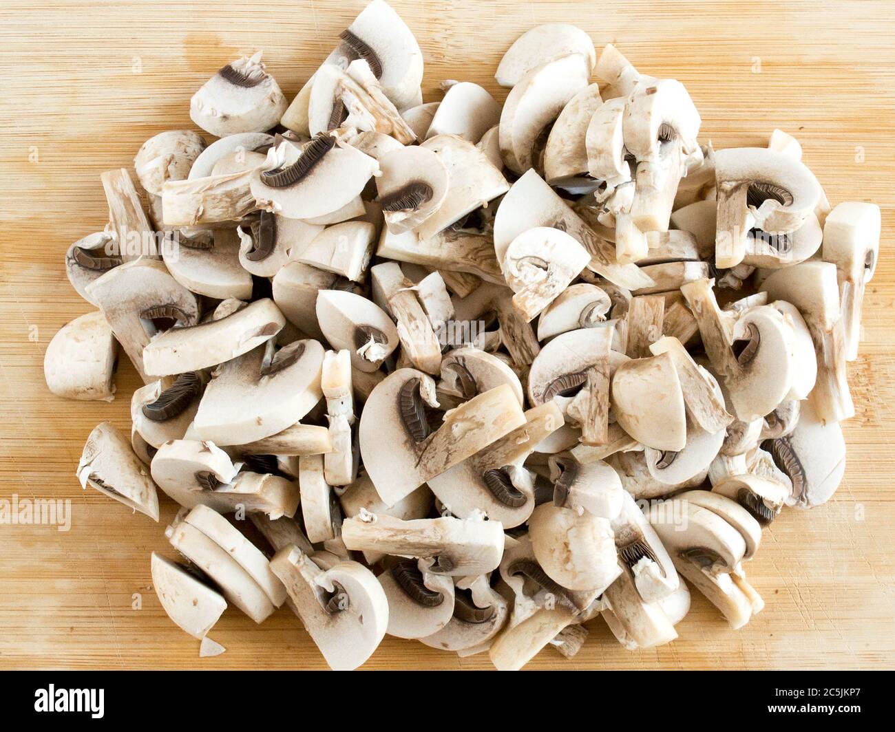 Champignons affettato su un bordo di legno. Funghi commestibili in pezzi, vista dall'alto. Foto Stock