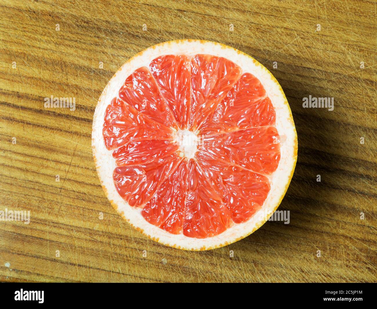 Mezzo grapefuit rosa centrato su una tagliere di legno Foto Stock