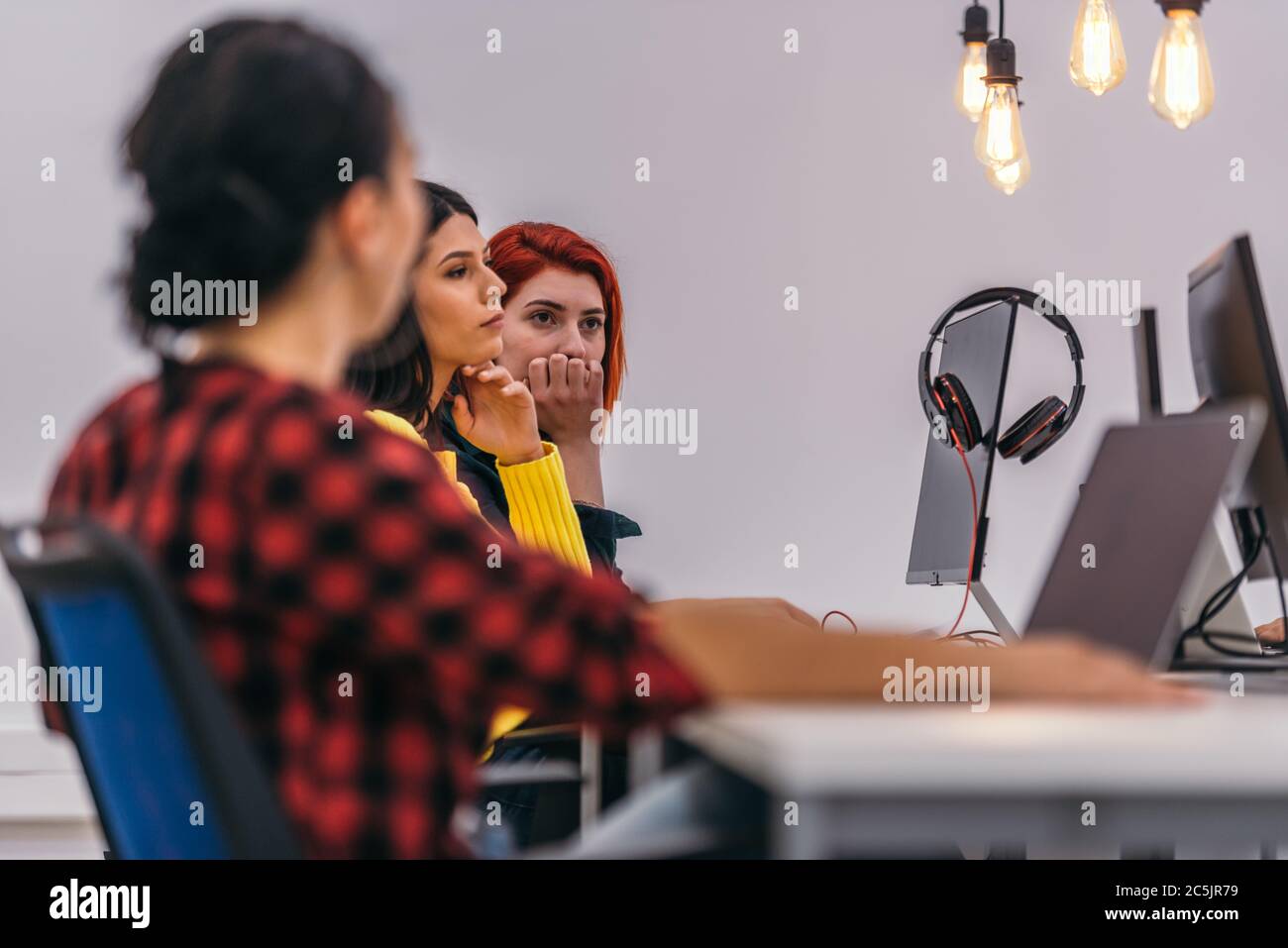 Le donne d'affari concentrate che siedono in un ufficio e che lavorano sul loro laptop Foto Stock