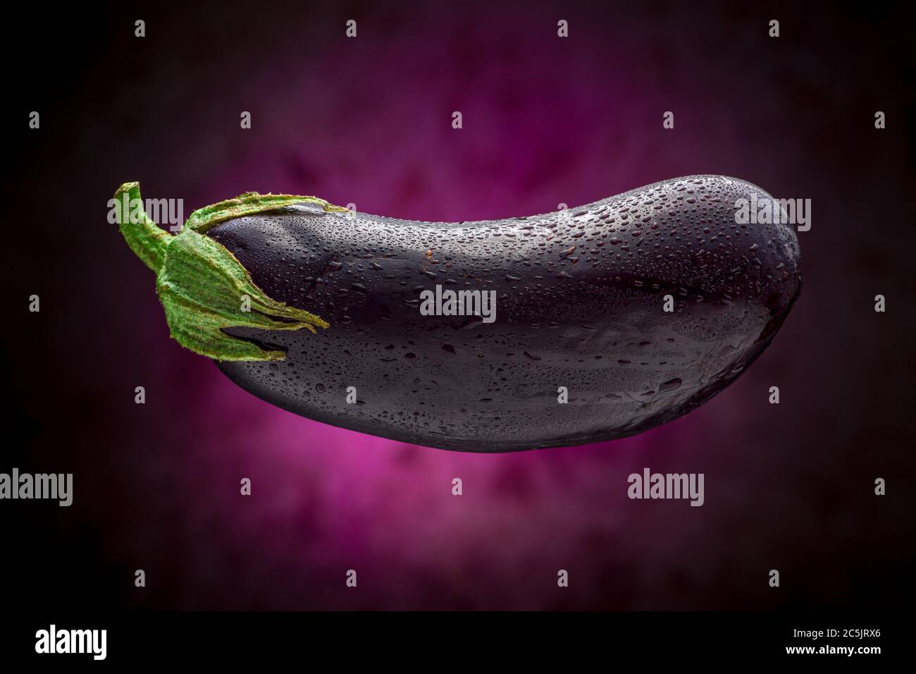 Wet Eggplant galleggianti con sfondo viola Foto Stock
