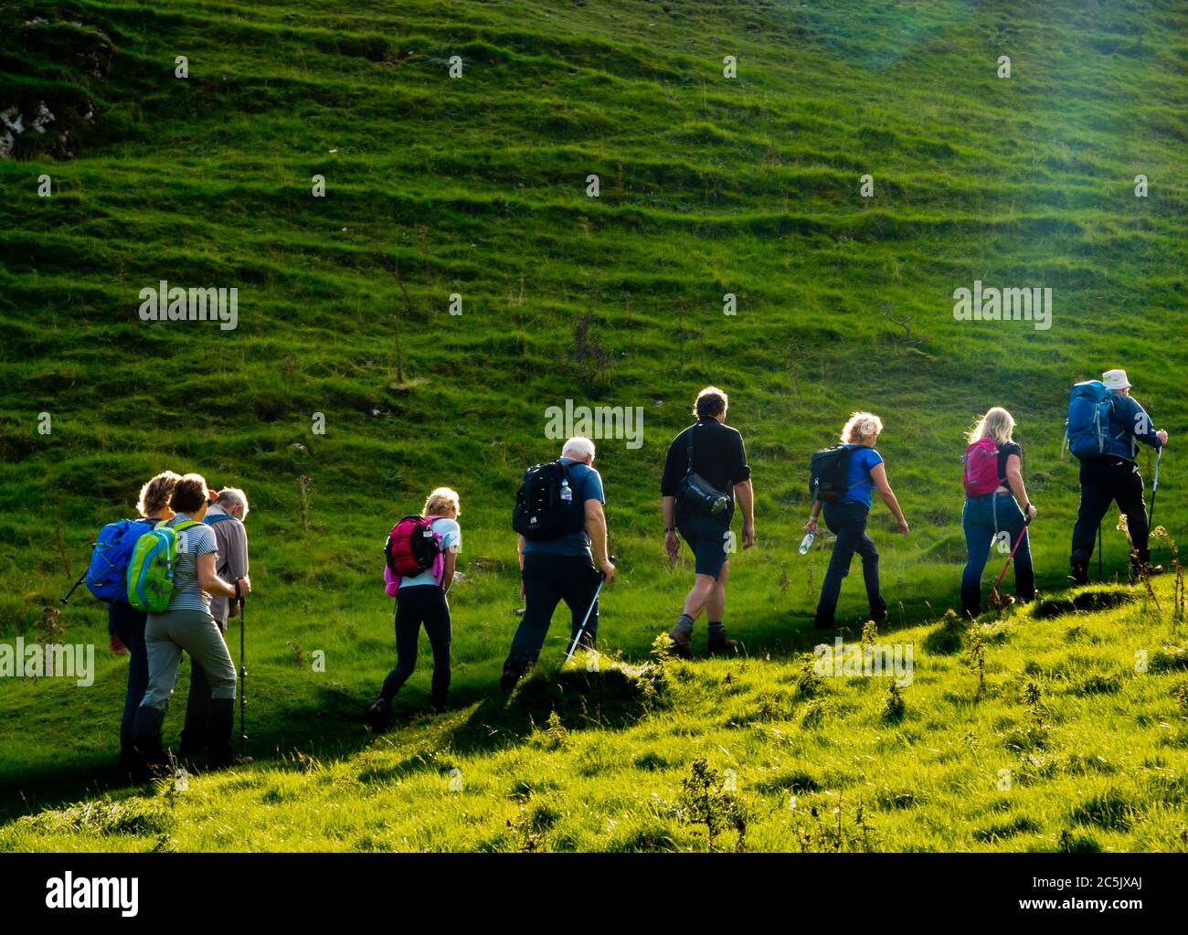 Gruppo di escursionisti che arrampicano su una collina verde nel Peak District National Park Derbyshire Inghilterra UK Foto Stock