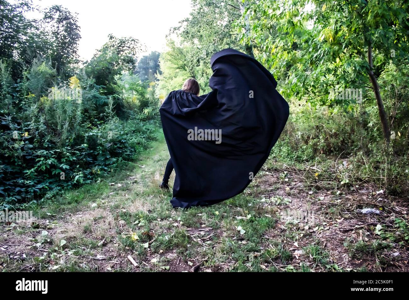 Una ragazza in un capo nero sulla natura. Una ragazza in un cappuccio. Danger.Fantasy Foto Stock