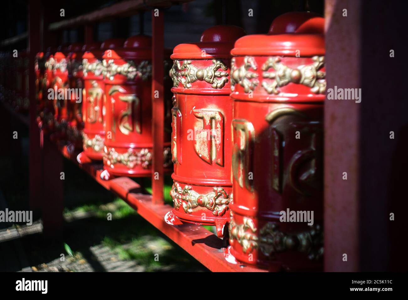 Tamburo di preghiera in un tempio buddista. Khurde rosso al sole. Mani tamburo Foto Stock