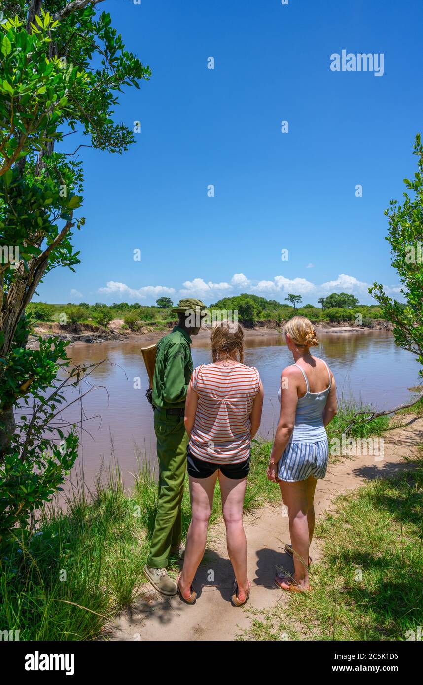 Turisti e ranger del parco che guardano agli ippopotami e ai coccodrilli nel fiume Mara, nel triangolo di Mara, nella riserva nazionale di Masai Mara, in Kenya, Africa orientale Foto Stock