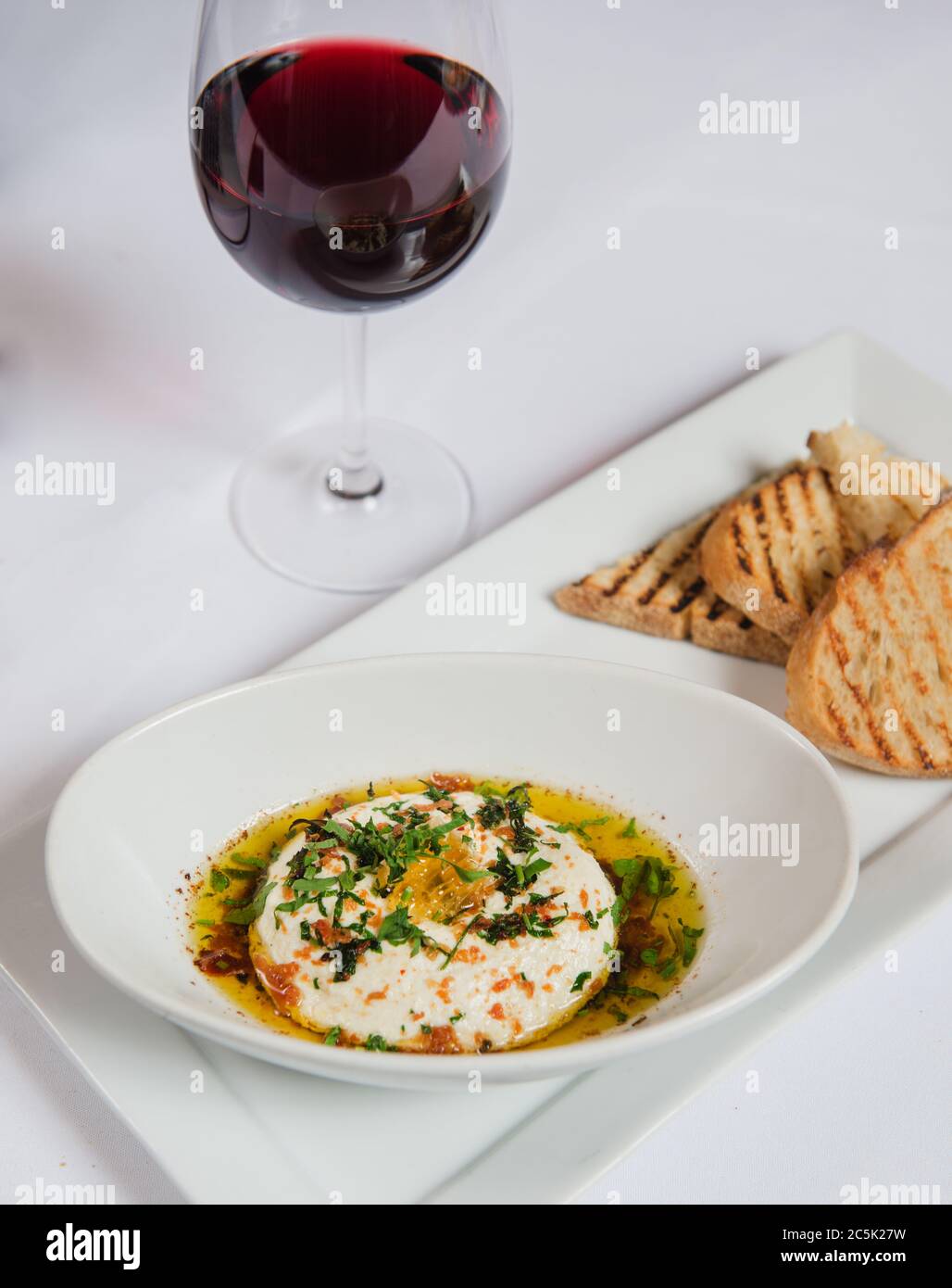 Ricotta con olio d'oliva, erbe, pane e vino rosso Foto Stock