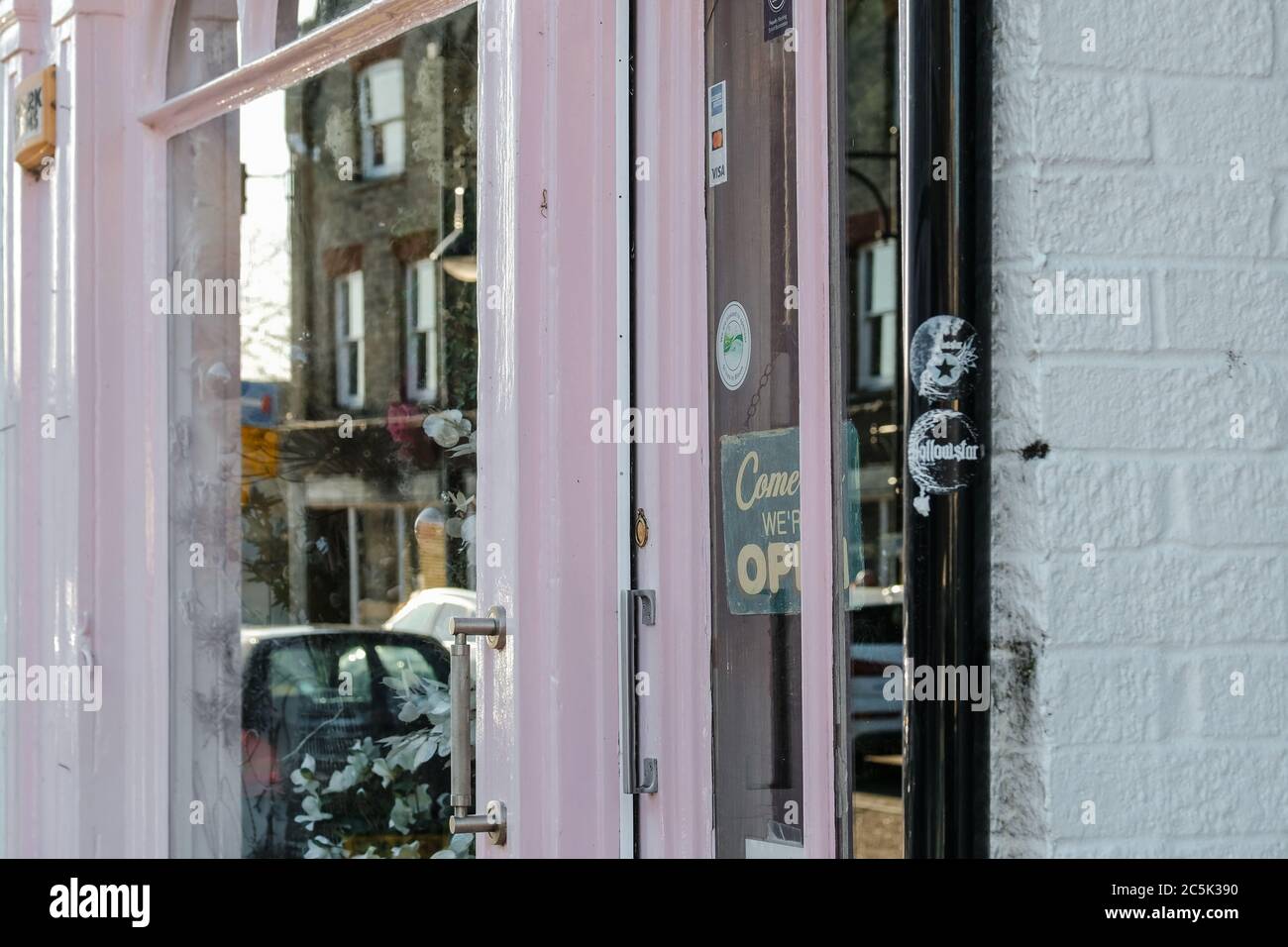 Primo piano di un piccolo negozio di strada e porta d'ingresso. Dipinta di  rosa, la vetrina riflette altri affari in questa strada trafficata Foto  stock - Alamy