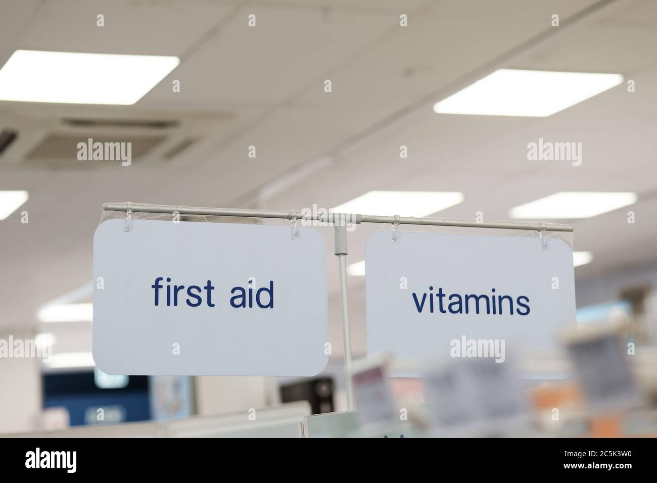 Fuoco superficiale di un primo soccorso e segno di vitamine situato all'interno di un negozio di farmacia ben noto al dettaglio. Foto Stock