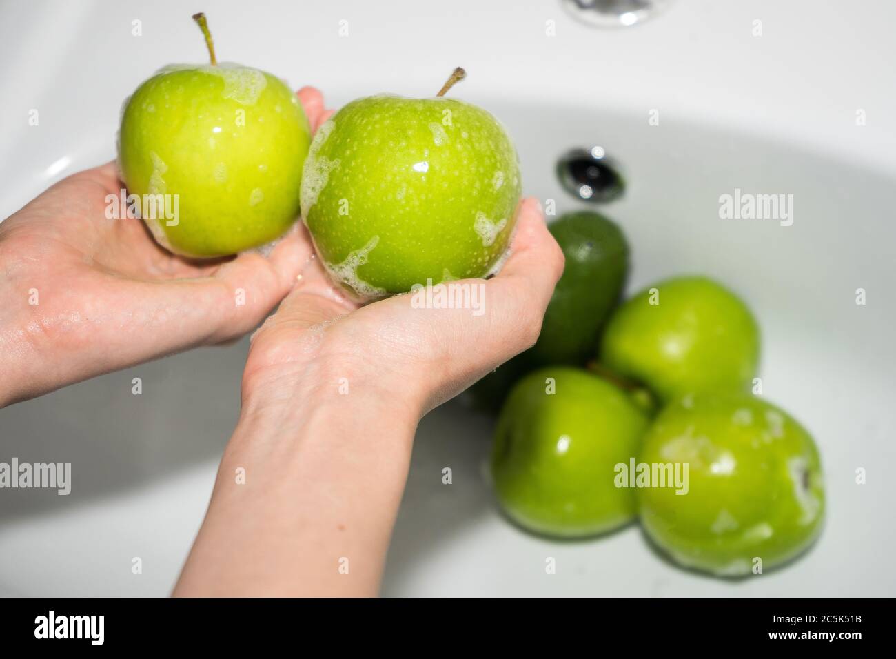 Lavare la frutta. Mani e mela verde saponata Foto Stock