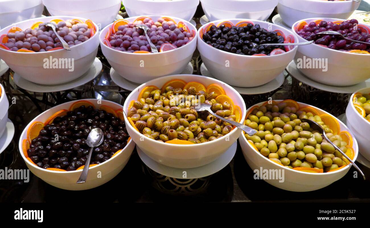Assortimento di varietà diverse di olive fresche e salutari in ciotole bianche Foto Stock