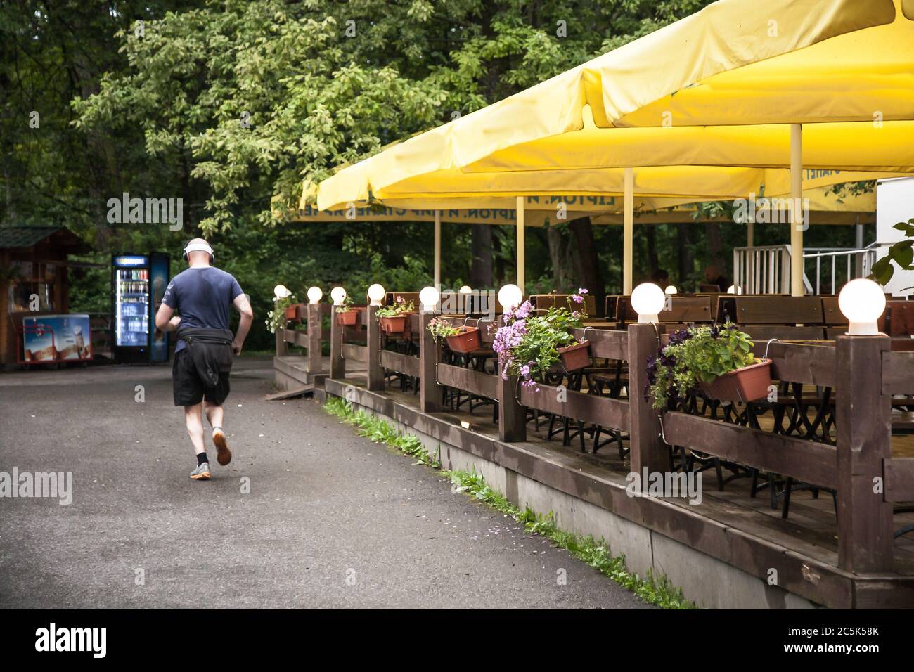 un anziano scherza dal retro in un parco, passa davanti a una birreria. allegoria: una scelta a favore dello sport, invece di alcol. Foto Stock