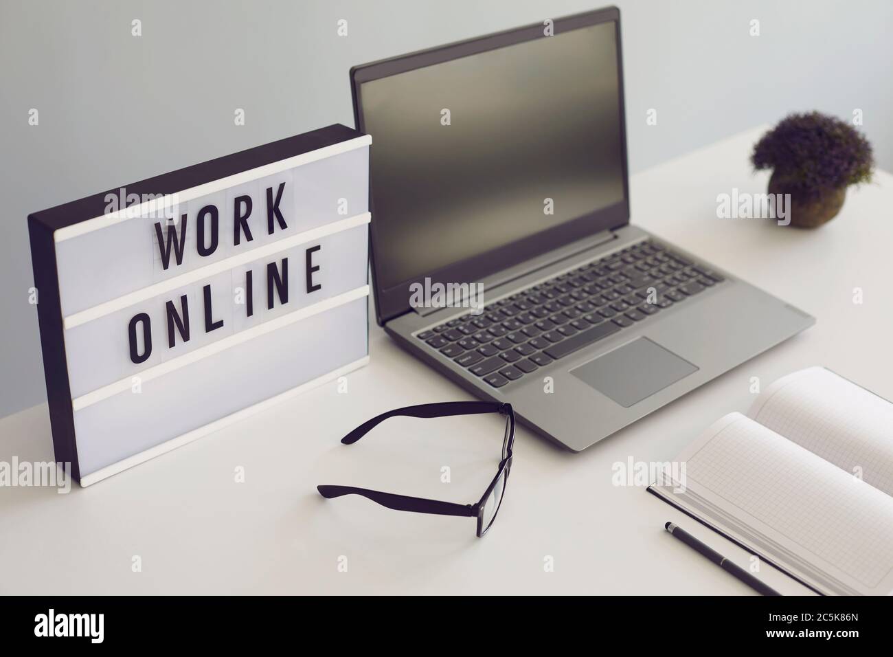 Concetto di lavoro online. Posto di lavoro con notebook e libri di occhiali da laptop sul tavolo. Foto Stock