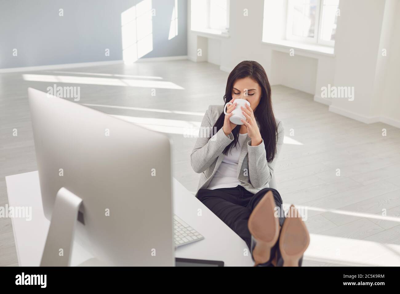 Donna d'affari rilassante che ama il caffè sul posto di lavoro in ufficio Foto Stock