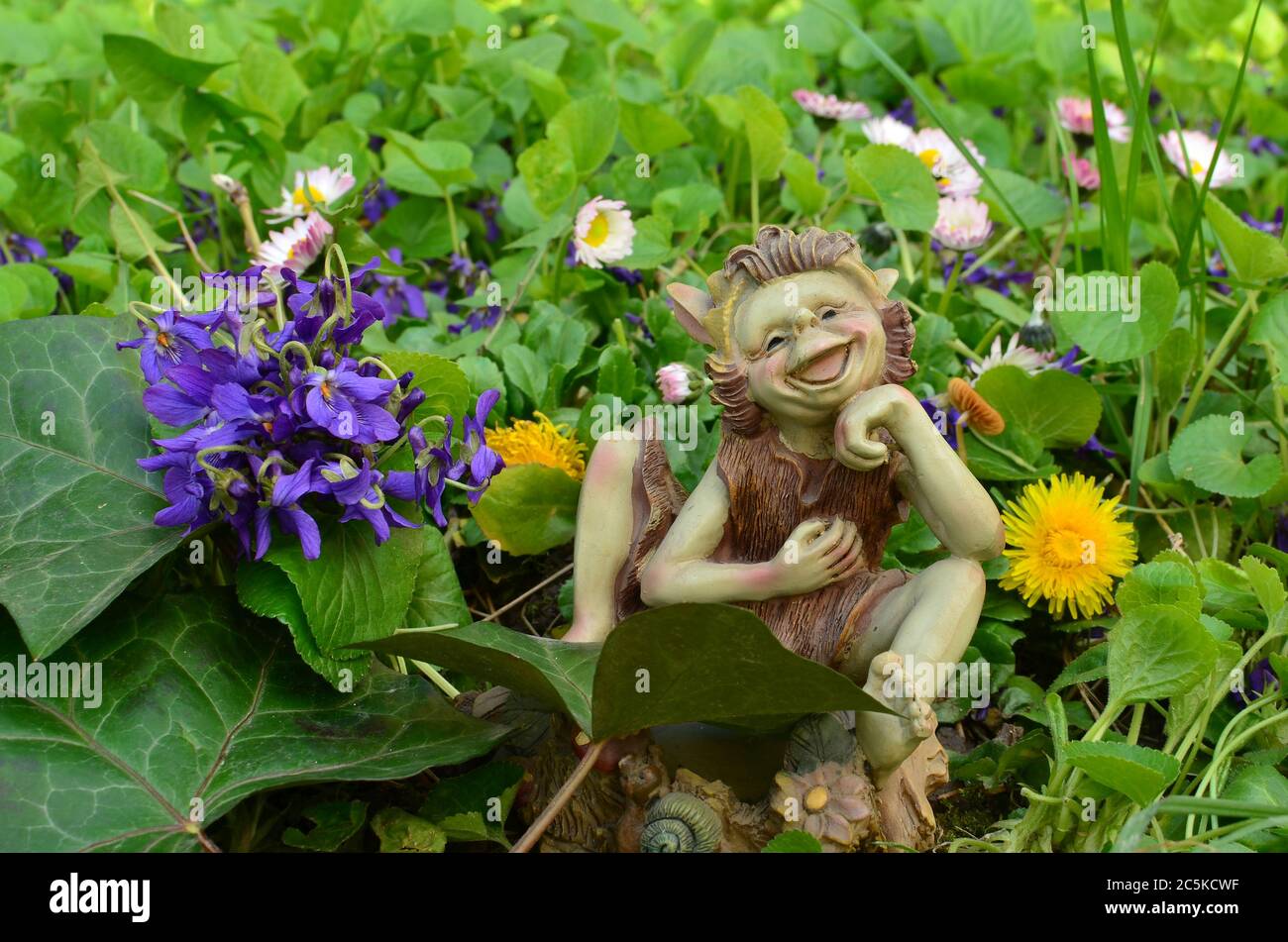 Bouquet di violette profumate con foglie di Ivy e bambola di elfo su un prato Foto Stock