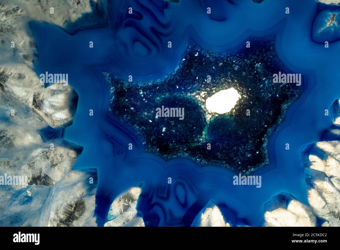 Macro foto di una roccia di agata blu e bianca. Ho illuminato i cristalli per far rischiare le texture minerali e i colori blu. Foto Stock