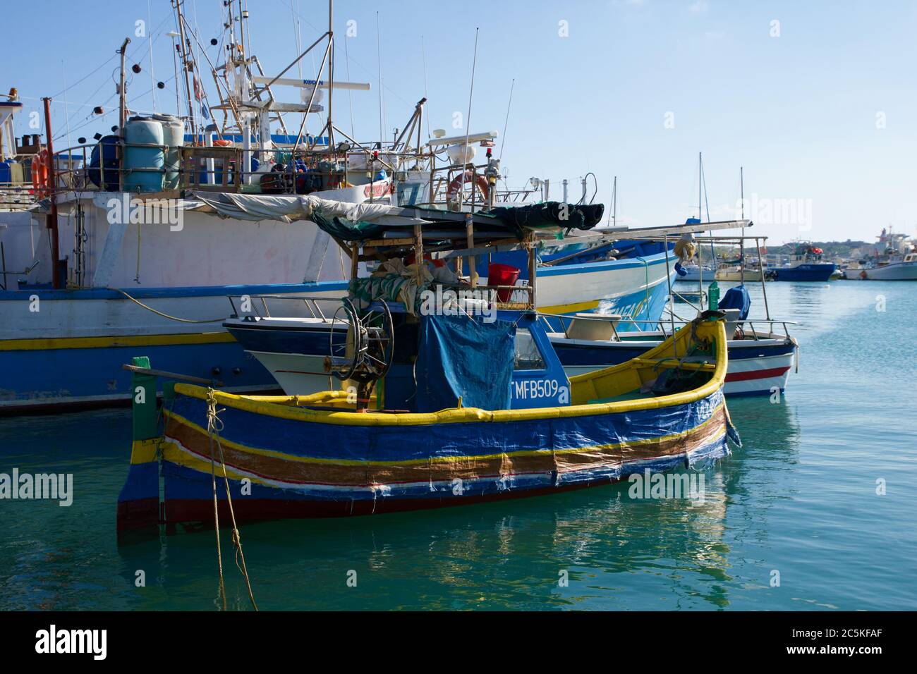 MARSAXLOKK, MALTA - DEC 31, 2019: Mercato Marsaxlokk con le tradizionali barche da pesca Luzzu in una bella giornata invernale con cielo blu e mare verde Foto Stock