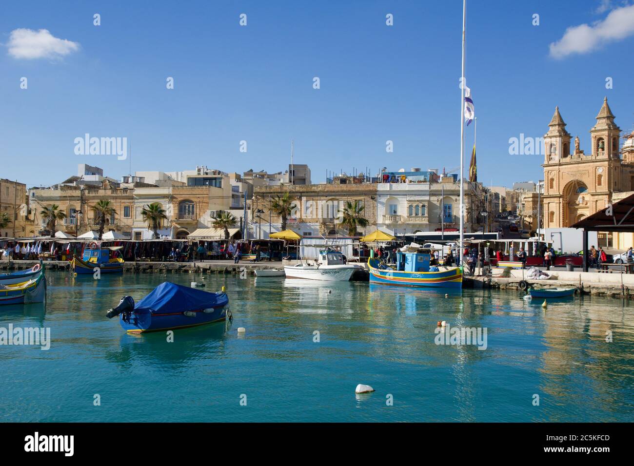 MARSAXLOKK, MALTA - DEC 31, 2019: Mercato Marsaxlokk con le tradizionali barche da pesca Luzzu in una bella giornata invernale con cielo blu e mare verde Foto Stock