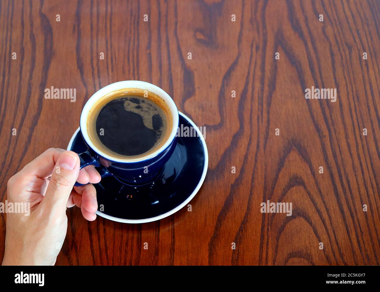 Tenere una tazza di caffè caldo sul tavolo di legno Foto Stock