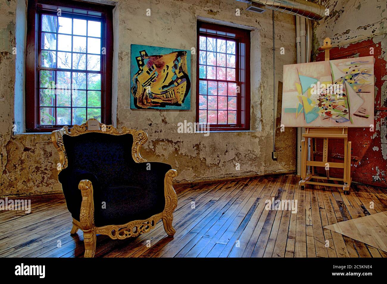 Vista di uno studio d'arte con una sedia vuota e pittura su un cavalletto. Foto Stock