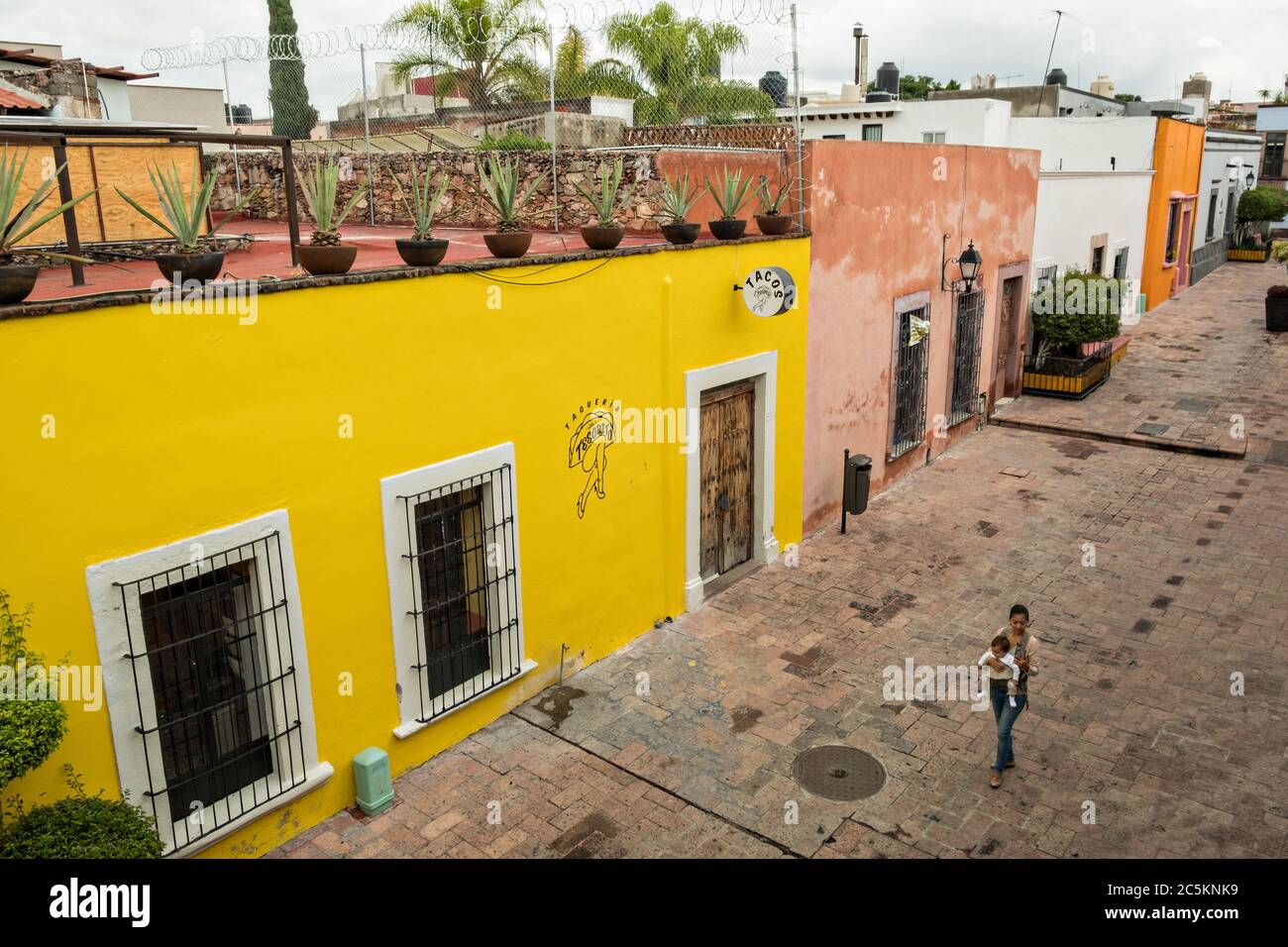 Una donna cammina lungo un vicolo colorato nella vecchia sezione coloniale di Santiago de Queretaro, Stato Queretaro, Messico. Foto Stock