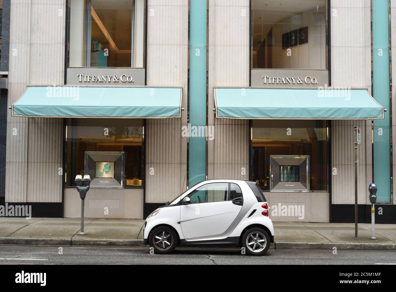 Una Smart car bianca e grigia si trova parcheggiata fuori dal negozio di gioielli Tiffany & Co. Nel centro di Vancouver, British Columbia, Canada. Foto Stock