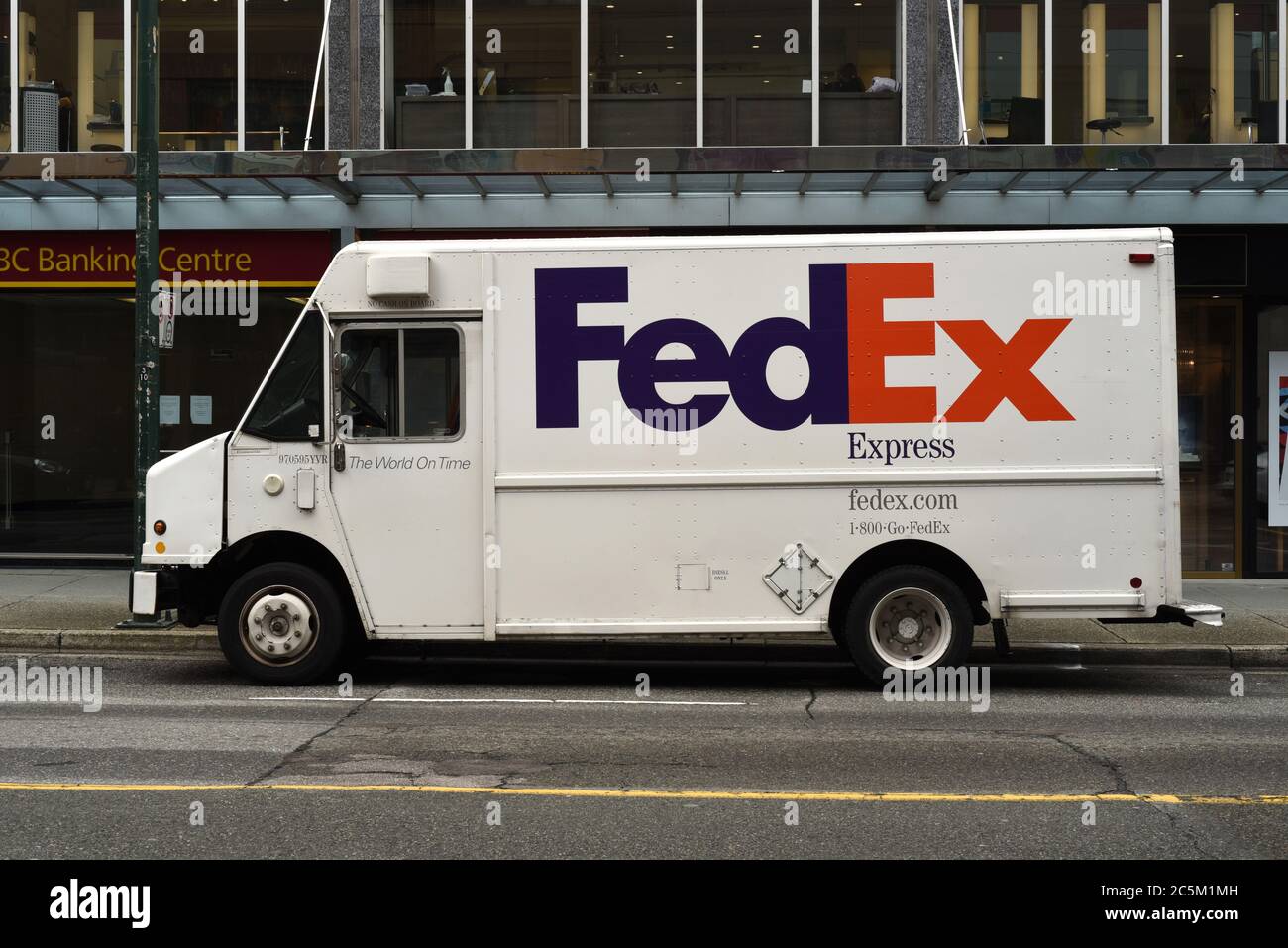 Un corriere FedEx Express per la consegna dei pacchi si trova parcheggiato in una strada del centro di Vancouver, British Columbia, Canada, fuori da un centro bancario CIBC. Foto Stock