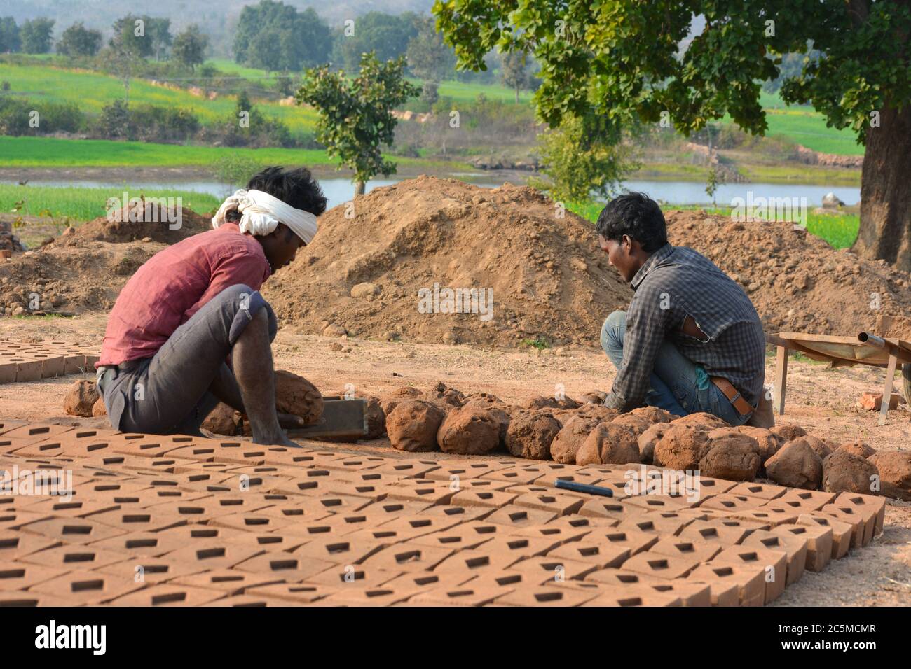 TIKAMGARH, MADHYA PRADESH, INDIA - 07 FEBBRAIO 2020: Uomini indiani felici non identificati che fanno i mattoni della casa a mano usando una muffa e argilla umida. Foto Stock