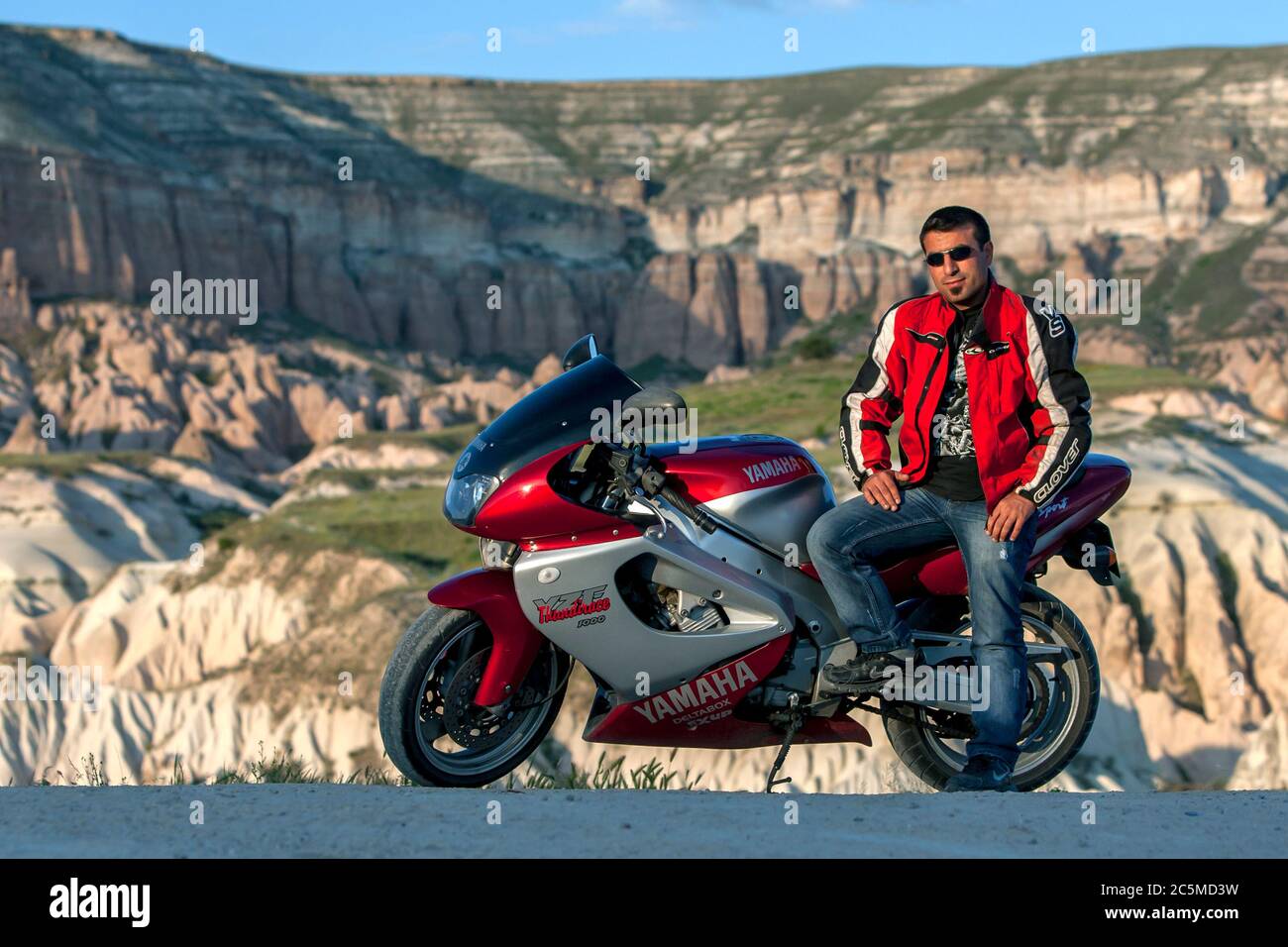 Un uomo turco si siede sulla sua moto vicino a Goreme nella regione della Cappadocia in Turchia. La Cappadocia è famosa per i suoi magnifici paesaggi. Foto Stock