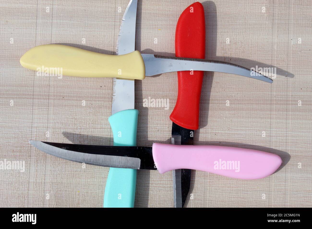 I coltelli colorati chiudono l'esposizione su una superficie di tessitura bianca. Il display del coltello trinciatrice e trinciatrice è illuminato. Foto Stock