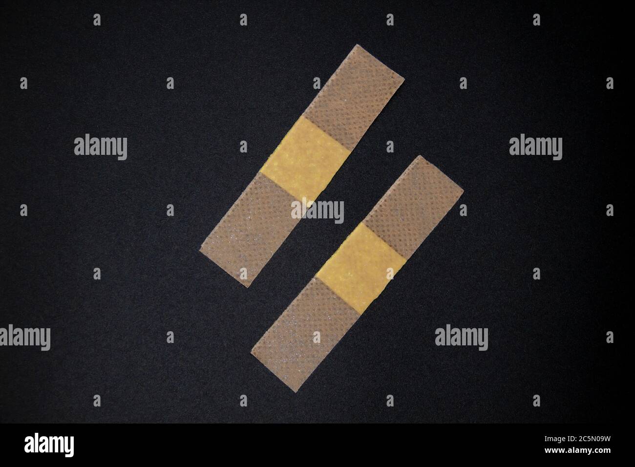 Due bende adesive su sfondo nero. Immagine di stock di bende adesive mediche. Immagine di cerotti medici incollati in una linea Foto Stock
