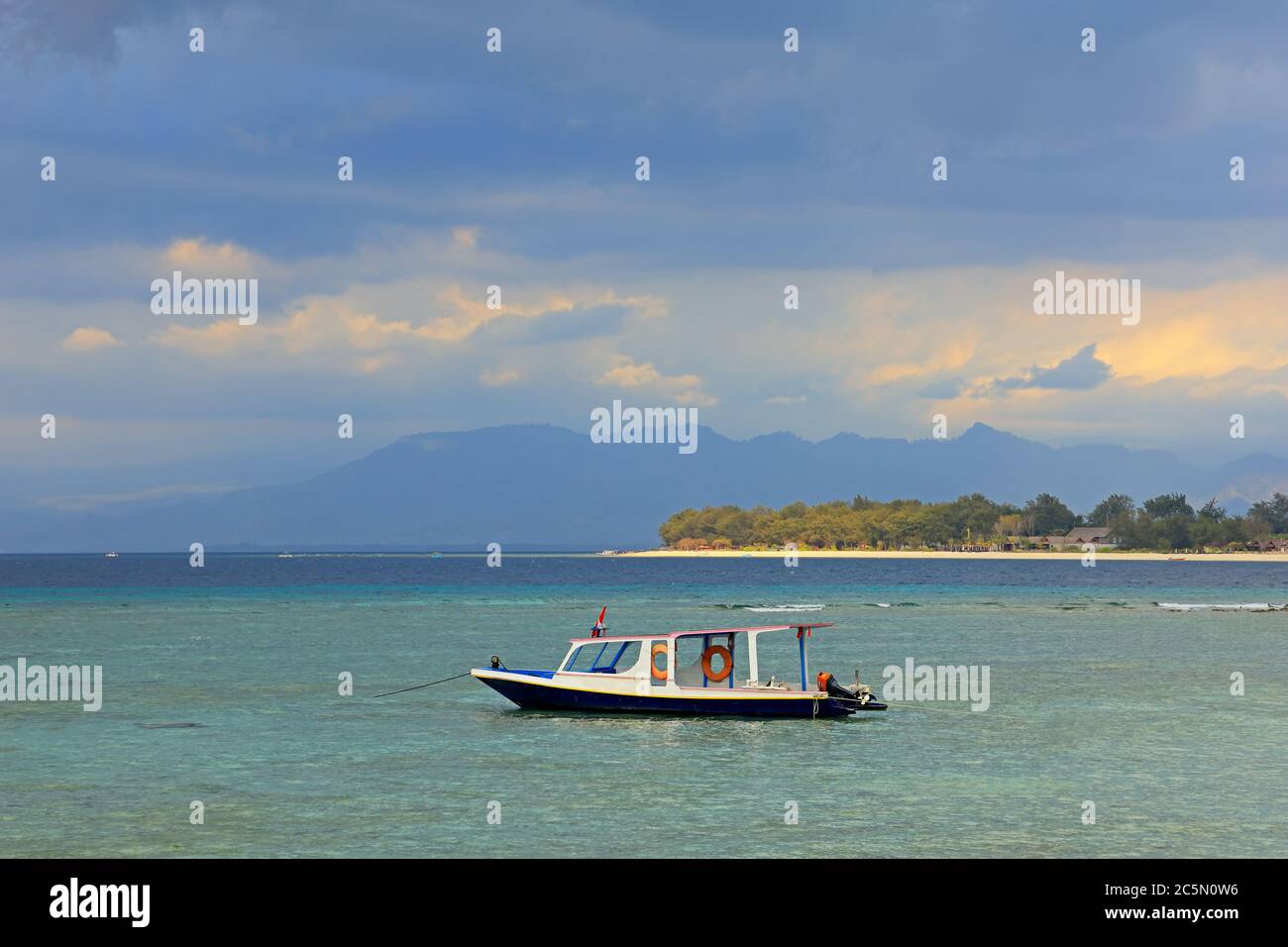 Isola tropicale indonesiana panoramica con barca ancorata contro un cielo scuro con nuvole Foto Stock
