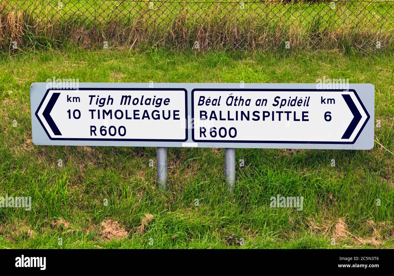 Destinazione indicazioni stradali per Timoleague e Ballinspittle in lingua gaelica e inglese, contea di Cork, Repubblica d'Irlanda. Eire. Foto Stock